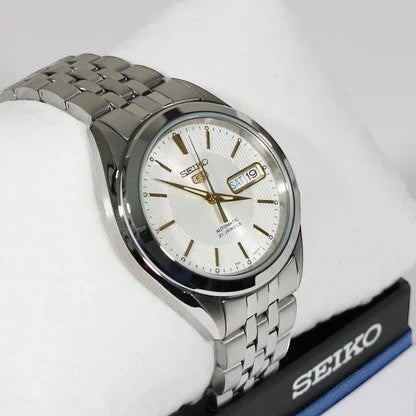 Reloj automático Seiko 5 de DEL MORAL | RELOJES con esfera blanca nacarada, detalles dorados y pulsera de acero inoxidable. Ventana de día y fecha.
