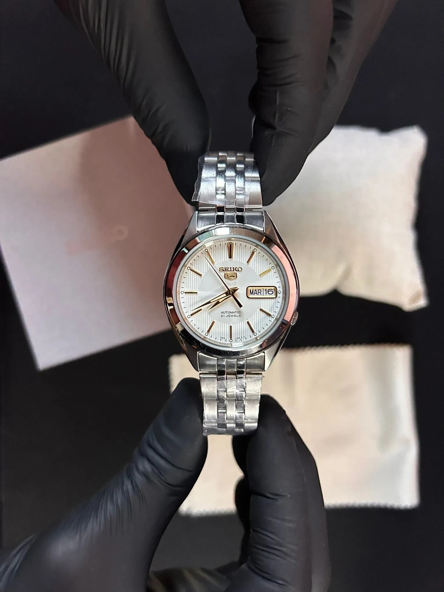 DEL MORAL | RELOJES Seiko 5 automático con esfera blanca nacarada, detalles dorados y pulsera de acero inoxidable.